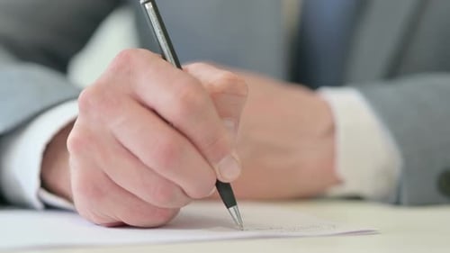 Nahaufnahme eines Geschäftsmannes, der mit Stift auf Papier schreibt