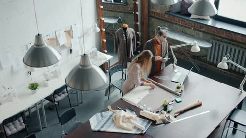 Top View of Tailors Man and Woman Working in Studio Talking Making New Garments
