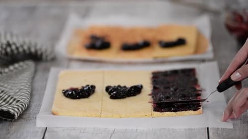 Girl Spreading Jam on a Flat Sheet of Cake To Make a Cake with Vertical Layers at Home