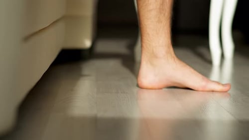 Man's Bare Feet on Wood Floor in Morning