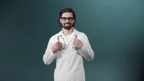 Porträt eines selbstbewussten jungen Arztes in Brille und mit Statoskope auf grünem Hintergrund
