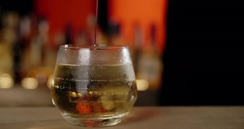 Liquor being poured into a glass with ice