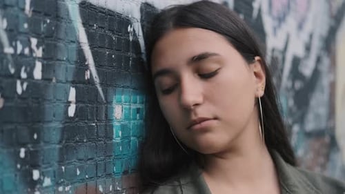 Portrait of a Young Stylish Hipster Girl Near the Wall with Graffiti. Close-up