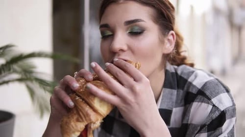 Woman Enjoying Croissant at Outdoor Cafe