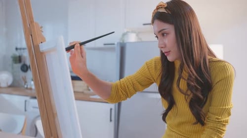 Woman Painting Picture on Canvas at Home