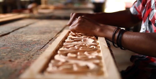 Artisan Hand Carving Intricate Wood Design at Workbench