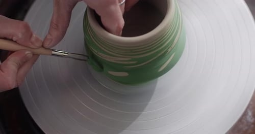 Potter sculpte un motif sur une carafe rotative Le volant de Potter à Workshop Potter fabrique de la céramique dans Slow