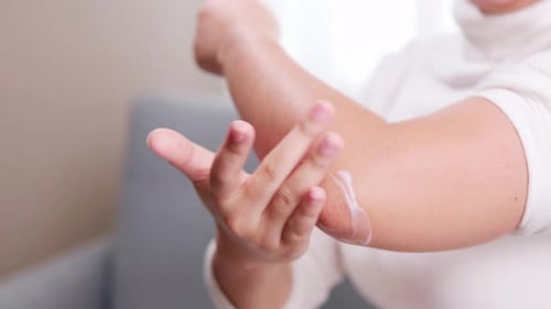 Detalle de mujer dando crema analgésica en el codo debido al dolor durante el armado.