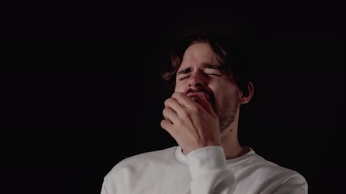 Jeune homme tendance bâillant extrêmement, geste fatigué, proche, fond noir