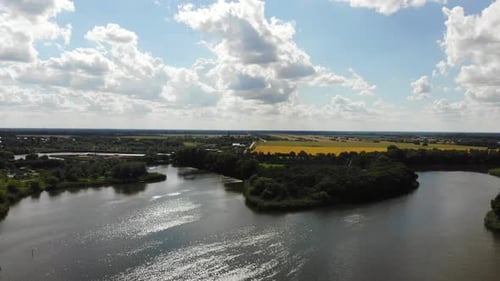 Flight in the countryside over a pond and a field.