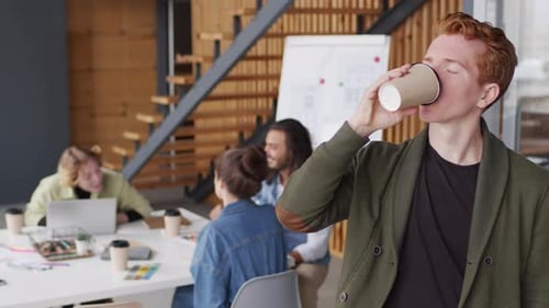 Young Adult Drinking Coffee in Modern Office