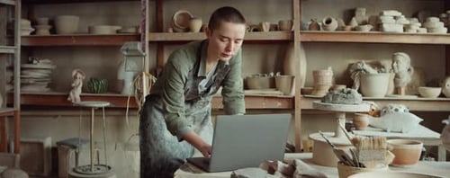 Femme potière utilisant un ordinateur portable dans un atelier