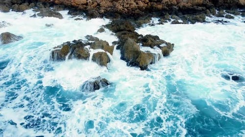Sea Waves Washes the Rocky Shore Above Aerial Shot Flying Over Coastline Cliffside with Blue Pure