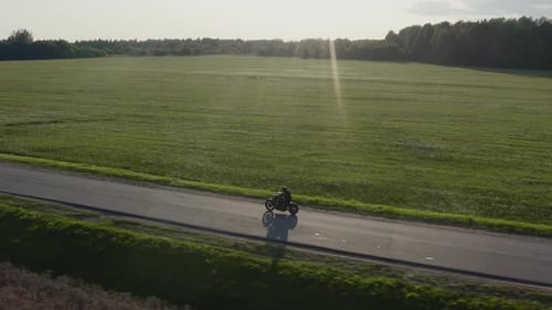 çMan Rides a Motorcycle on a Sunset Country Road Aerial Dron Tracking Shot. .ç
