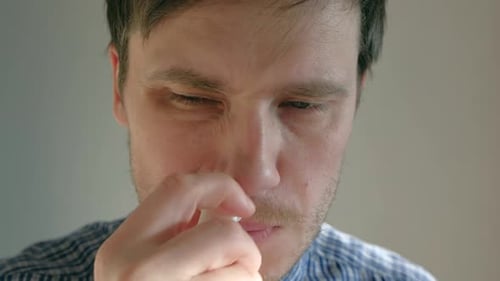 Un homme éclabousse un médicament dans le nez qui coule