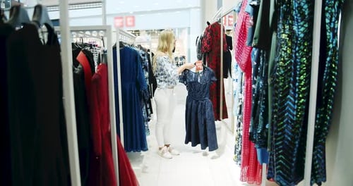 Woman Shopping for a Dress in Clothing Store