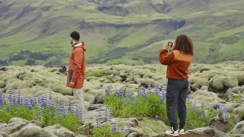 Couple Taking Pictures Among Mossy Rocks and Wildflowers