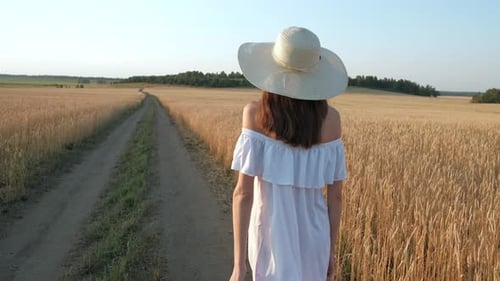 Beautiful Woman Goes to Field of Ripe Golden Wheat