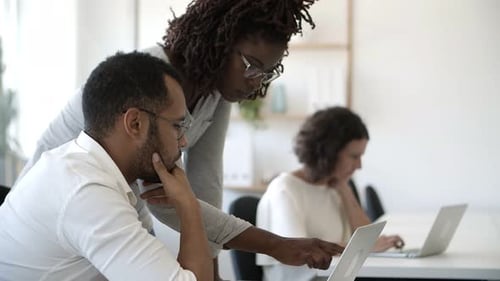 Coworkers Collaborate on Laptop in Bright Office