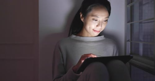 Woman use of tablet computer at night