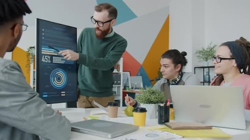 Male Speaker Making Presentation in Office Pointing at Digital Screen with Information