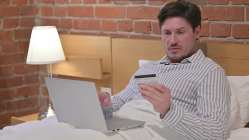 Man in Bed Frustrated with Online Shopping