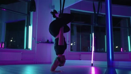 Young Woman Practicing Aerial Yoga in Neon Studio