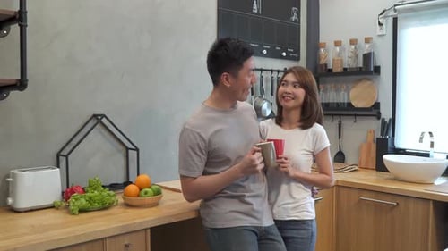 Happy Couple Talking Together in Kitchen with Drinks