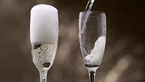 Champagne Pouring in Two Glasses of Steamy Green Bottle. Bokeh Background. Close Up