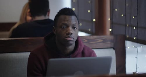 Bored Young Man with Laptop in Cafe