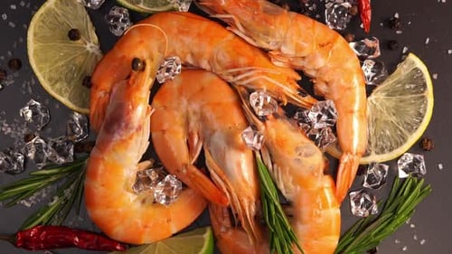 Top View of Fresh Raw Orange Prawns in Ice Rotates on Stone Cutting Board