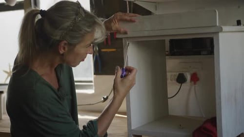Woman Assembling Furniture with Screwdriver in Workshop