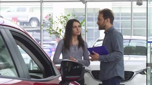 Woman and Salesman Discussing Car Purchase in Showroom