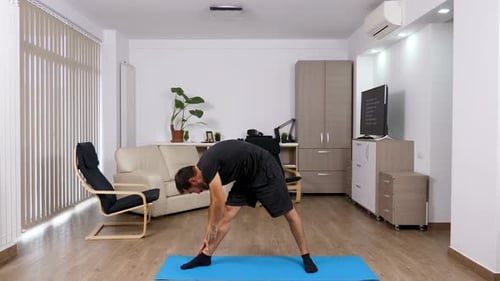 Man Doing Yoga Routine on a Mat Indoors