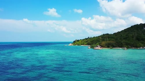 Paradise tropical island with lush vegetation and palm trees, rocky coastline washed by blue turquoi