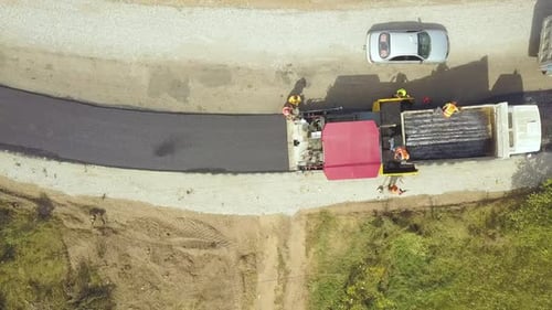 Aerial View of New Road Construction with Workers and Asphalt Laying Machinery at Work