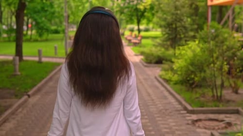Back View Student with Earphone Walks in City