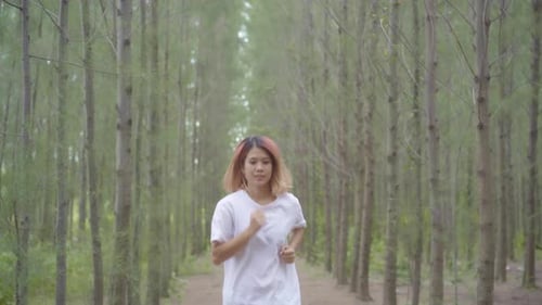 Healthy young athletic sporty Asian runner in sports clothing running and jogg on forest trail.