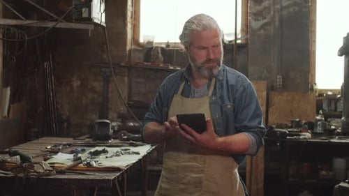 Man with Gray Hair Using Tablet in Workshop