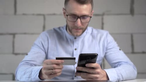 De perto, um homem transfere dinheiro para um cartão usando um telefone celular