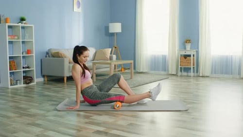 Woman Uses Foam Roller for Leg Exercise at Home