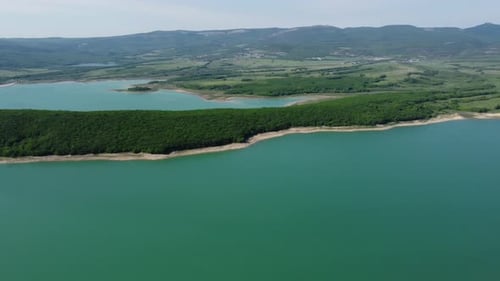 Aerial View on Water Reservoir at Mountain Valley Covered with Green Spring Forest