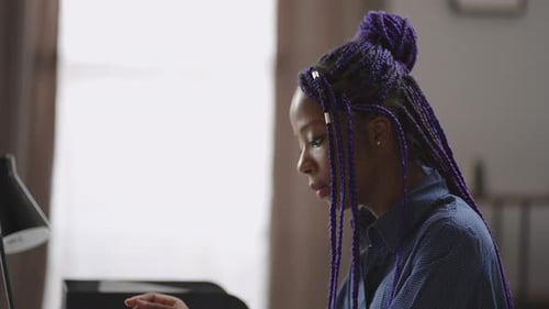 Femme noire moderne avec des dreadlocks violets travaille avec un ordinateur portable à la maison Jeune femme d'affaires est