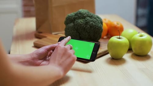Closeup of Woman's Hand Browsing Smartphone with Chroma Key on