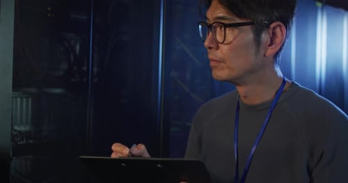 Adult Writing on Clipboard in Server Room