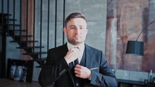 Man in Suit Adjusting Tie Indoors