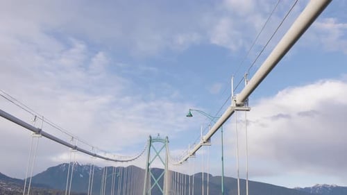 Driving Across Lions Gate Bridge with Mountains and Blue Sky in Background