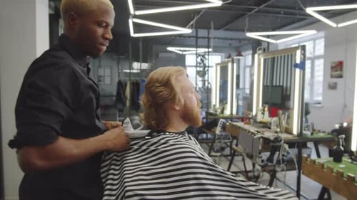 Barber Putting Haircutting Cape on Client