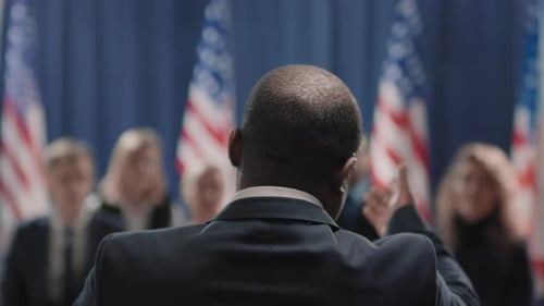 Speaker Addresses Audience with American Flags