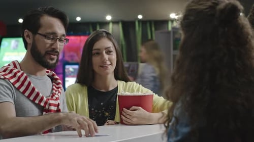 Couple Buys Tickets and Popcorn at Theater